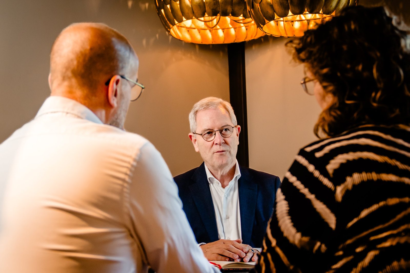 Periodiek verrekenbeding niet uitgevoerd: wat betekent dit voor je bedrijf? Robert Oosthout luistert naar twee mensen tijdens een gesprek.